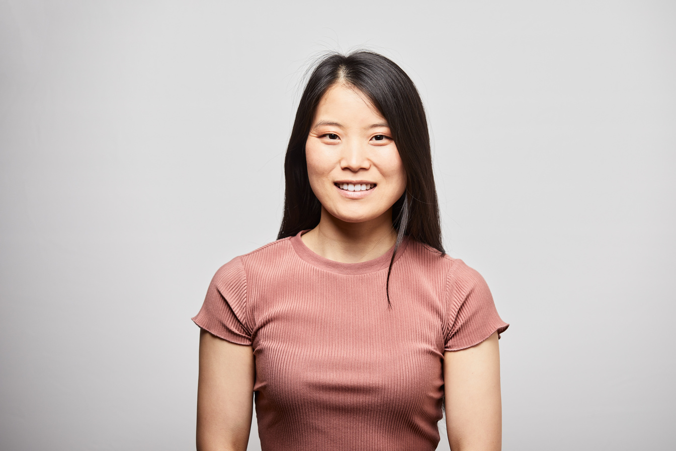 Young Chinese woman headshot on gray background.